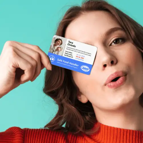 A woman playfully holds up a business card, sticking her tongue out.